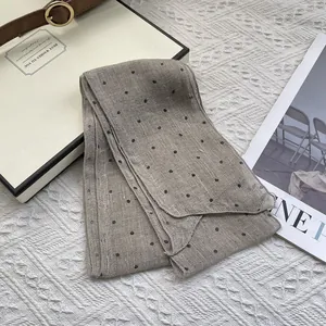 Detail shot of breathable pure linen scarf with black polka dots on light beige fabric