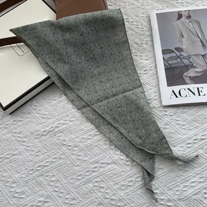 Close-up of light green floral cotton linen triangle scarf on white knit background