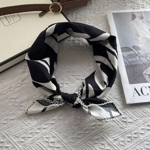Détail d'un foulard en soie à imprimé feuilles noir et blanc avec bordure en dentelle