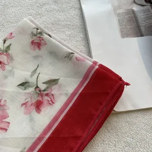 Close-up of floral cotton scarf showing breathable mesh texture and red overlock stitching