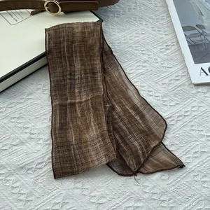 Detail of coffee brown linen-textured ribbon scarf on a white quilted background