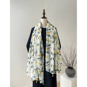 Écharpe en soie blanche avec imprimé citron et glands jaunes sur un mannequin