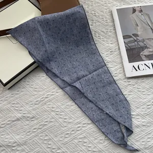 Detailed view of blue floral cotton scarf on white textured surface with gift box