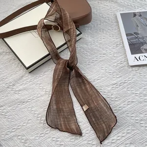 Detail of a brown pure silk scarf with fine texture and care label on a fashion magazine