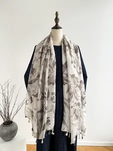 Close-up of linen silk scarf featuring gray floral prints and delicate tassel edges