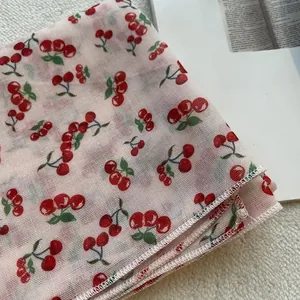 Dettaglio del tessuto a rete rosa con stampa di ciliegie e bordi rifiniti con cura