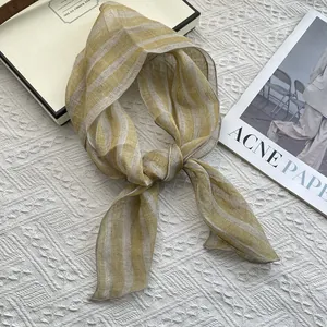 Detail of breathable yellow striped linen scarf on a minimalist white textured background