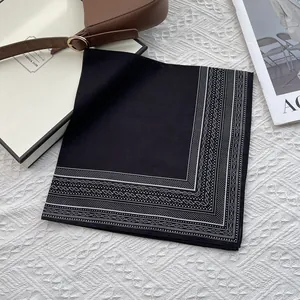 Elegante pañuelo de seda negro con diseño de cachemira blanco y borde, doblado