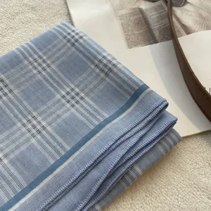 Detail of blue and white checkered cotton scarf showing fine rolled hem and soft texture