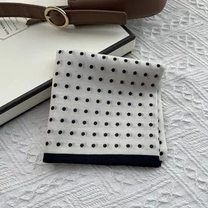 Elegant white square scarf with black polka dots displayed on a decorative gift box