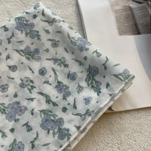 Detailed view of the fine cotton linen texture and delicate purple floral print on the scarf