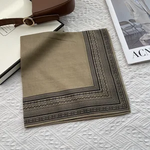 Detalle de pañuelo cuadrado de seda beige con estampado paisley sobre fondo blanco