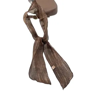 Brown 100% silk twilly scarf with horizontal texture tied on a leather handbag handle