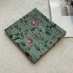 Dettaglio di sciarpa in cotone e lino verde con raffinati motivi floreali vintage e trama