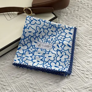 Detailed view of white cotton floral scarf with blue lace trim on a soft blanket