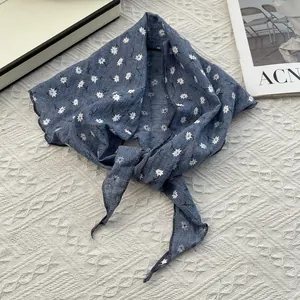 Detailed view of blue floral cotton linen bandana with white daisy pattern on knit background