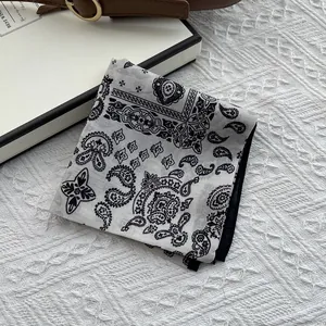 Detailed macro view of black and white paisley pattern silk scarf on textured surface