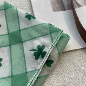 Detail of green clover print on semi-transparent mesh scarf with delicate rolled edges