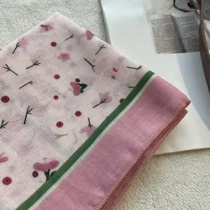 Close-up of lightweight floral cotton linen scarf with cherry blossom print and hemmed edges