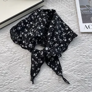 Detail of black floral triangle headscarf with white flower prints and hemmed edges