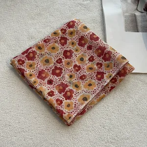 Dettaglio del foulard in cotone e lino con stampa floreale, pois rossi e bordi cuciti