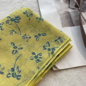 Detail of yellow floral cotton bandana with blue daisy prints and fine mesh texture