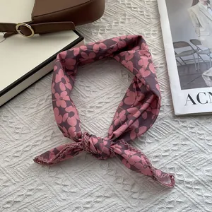 Detail of floral cotton scarf with lace trim showing the knotted styling on a white textured bed