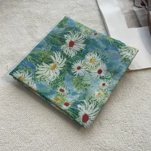 Detailed close-up of blue floral cotton scarf with daisy print on soft fabric texture