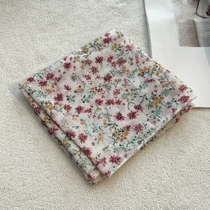 Dettaglio del foulard in cotone e lino con fiori rossi e gialli e bordi rifiniti in bianco