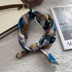 Détail d'un foulard en soie avec bordure dorée sur fond de tissu blanc texturé
