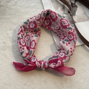 Detail of floral linen square scarf with red flowers on a soft pink background