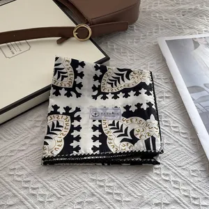 Folded cotton square scarf with geometric pattern and black lace trim in lifestyle setting