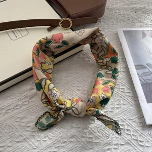 Détail d'un foulard floral jaune avec bordure en dentelle verte sur nappe blanche