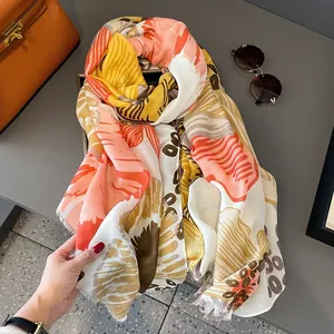 Longue écharpe ethnique à fleurs et pompons en coton et lin dans les tons orange