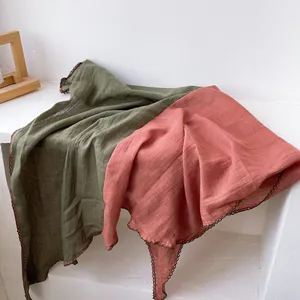 Detail van olijfgroene en roze linnen sjaals met delicate gehaakte kanten randjes