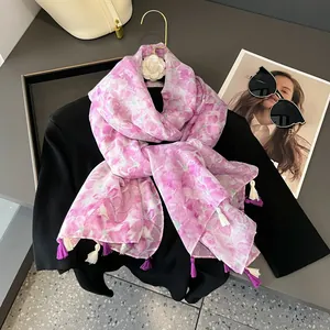 Pink floral print scarf with purple fringe tassels hanging on a golden hook display