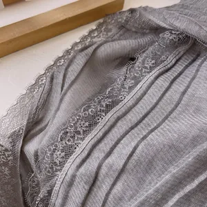 Close-up of pleated grey cotton scarf with delicate eyelash lace edges and soft texture