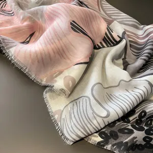 Détail d'une écharpe en lin aux motifs floraux roses avec des bords effilochés fins