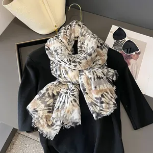 Dettaglio di una sciarpa tie-dye con frange abbinata a occhiali da sole e borsa di moda