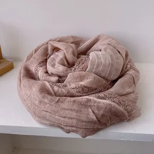 Detail of soft rose pink cotton linen scarf with elegant white lace trim texture