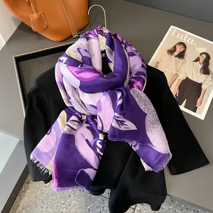 Détail d'une écharpe florale en coton et lin violet avec des franges fines sur un magazine