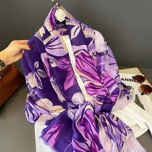 Détail d'une écharpe en soie à motif floral violet avec fini satiné et bords frangés