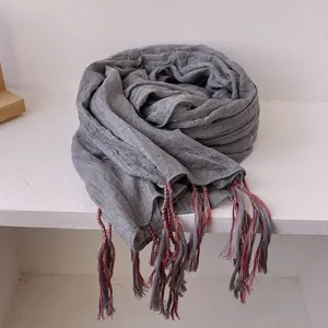 Close-up of dark grey cotton linen scarf with textured weave and colorful tassel trim