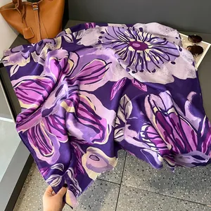 Détail d'une écharpe fleurie fine avec bords frangés et motif floral violet peint à la main