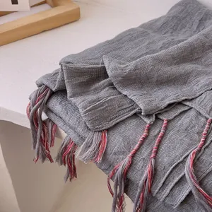 Close-up of gray cotton linen scarf showing wrinkled texture and colorful tassel details