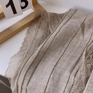 Detail of light brown cotton linen scarf with pleated texture and delicate lace edge