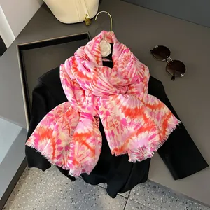 Dettaglio di sciarpa tie-dye sfumata rosa e arancio con frange su una gruccia elegante