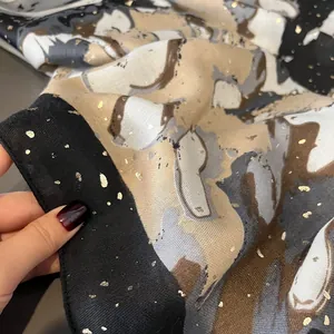 Detailed macro view of oil painting print scarf with gold foil accents and soft texture