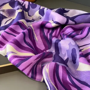 Gros plan d'une écharpe en coton et lin à fleurs mauves montrant texture et drapé