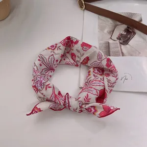Detail eines Vintage Baumwoll-Halstuchs mit Blumenmuster und roten Nähten auf Beige